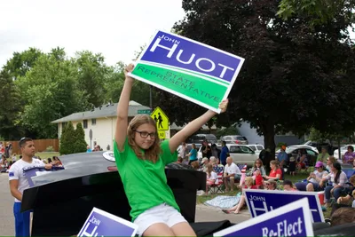 Young parade participant waving at supporters